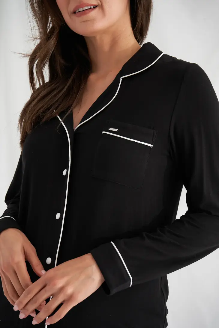 Women's black bamboo pajama set detail of front pocket with white trim and buttons. 