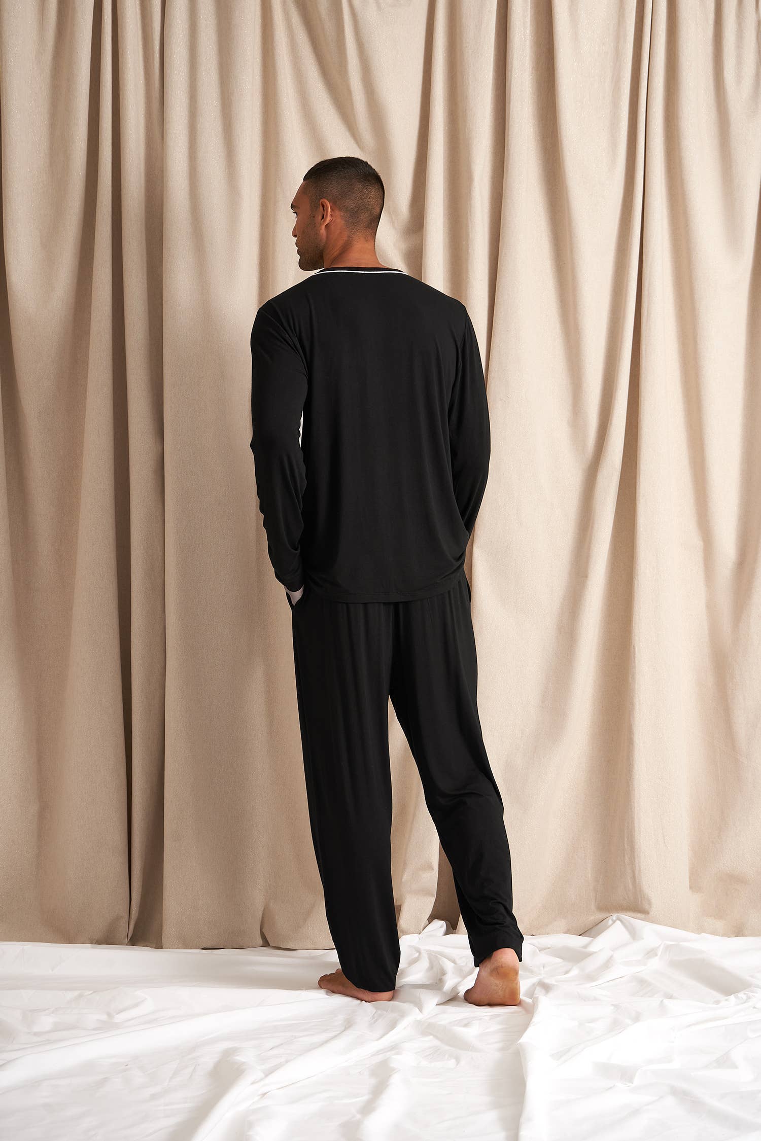 Men's black bamboo pajama set with long-sleeve top and full-length pants. White drawstring and piping detail. Front shirt pocket and pant pockets