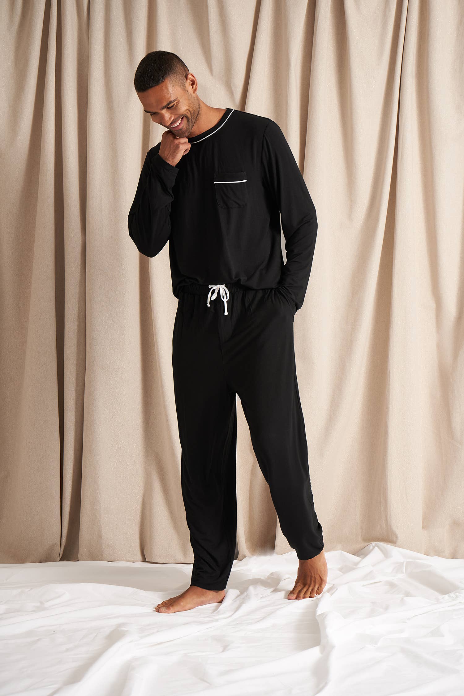 Men's black bamboo pajama set with long-sleeve top and full-length pants. White drawstring and piping detail. Front shirt pocket and pant pockets