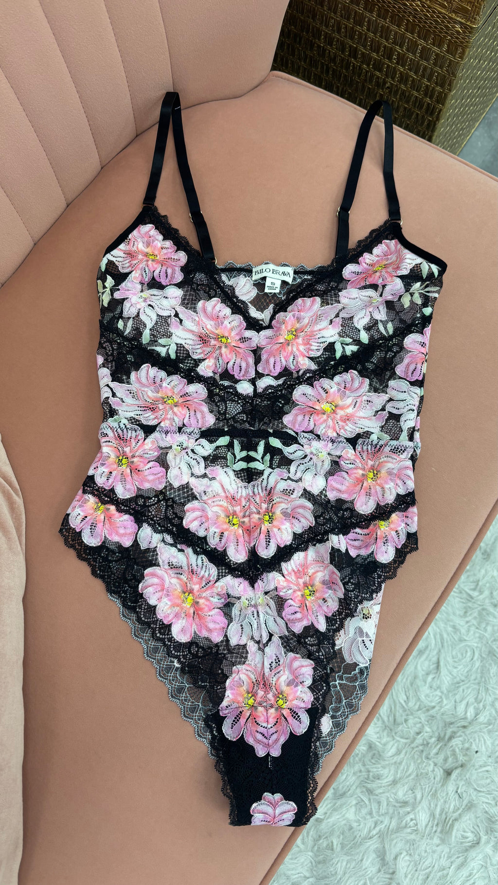 Women's pink and white floral teddy bodysuit with adjustable straps flat lay