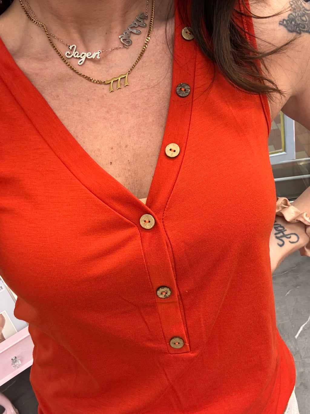 Women's orange v-neck tank top with button details close up