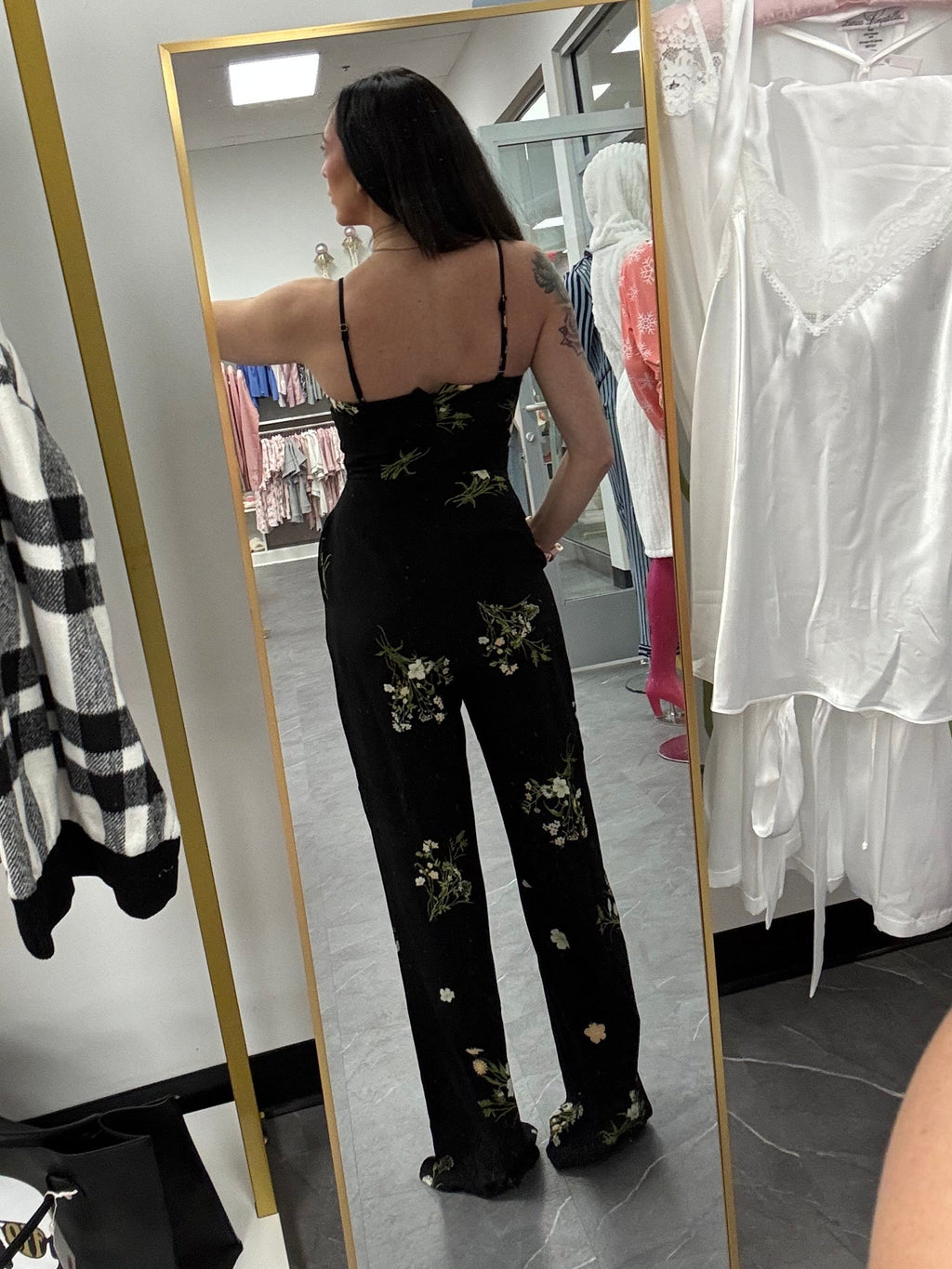Women's black floral romper jumpsuit with flared legs and removable straps. Silicone around top to help hold in place on model