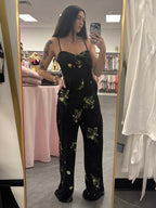 Women's black floral romper jumpsuit with flared legs and removable straps. Silicone around top to help hold in place on model