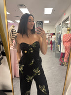 Women's black floral romper jumpsuit with flared legs and removable straps. Silicone around top to help hold in place on model