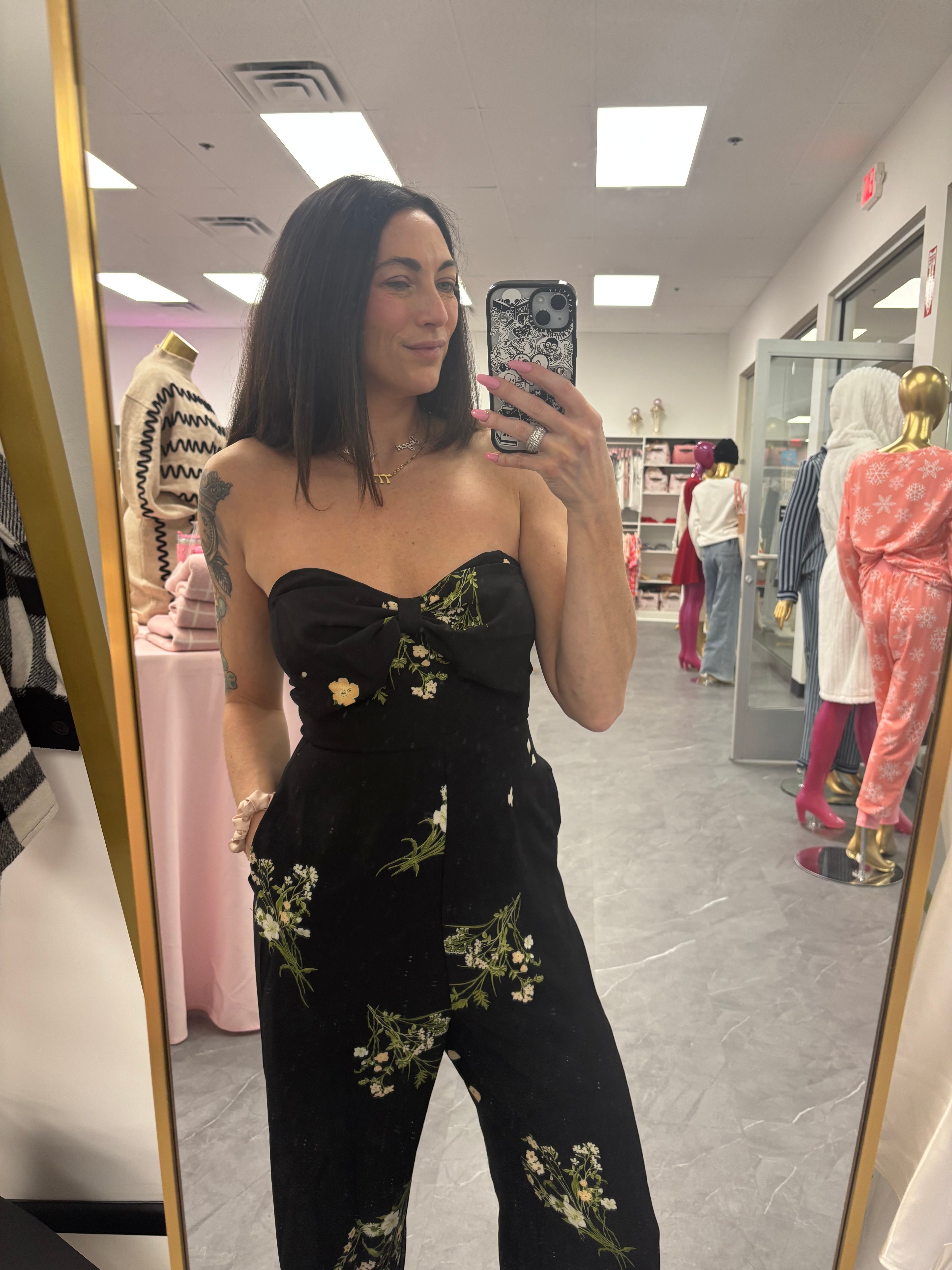 Women's black floral romper jumpsuit with flared legs and removable straps. Silicone around top to help hold in place on model
