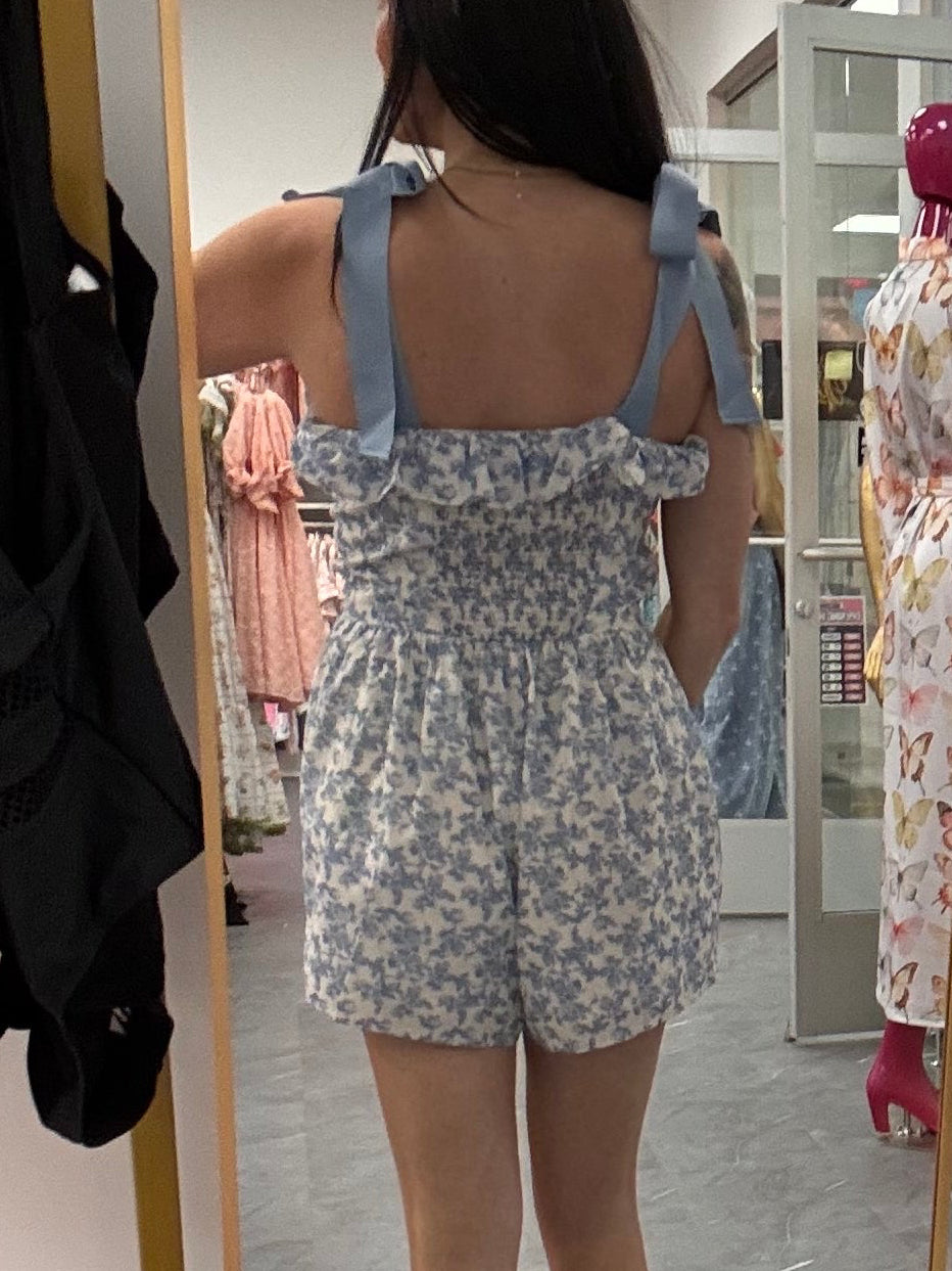 Women's blue floral romper with bow tie straps on model