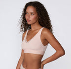 Women's blush pink pull over seamless bralette with lace side on model
