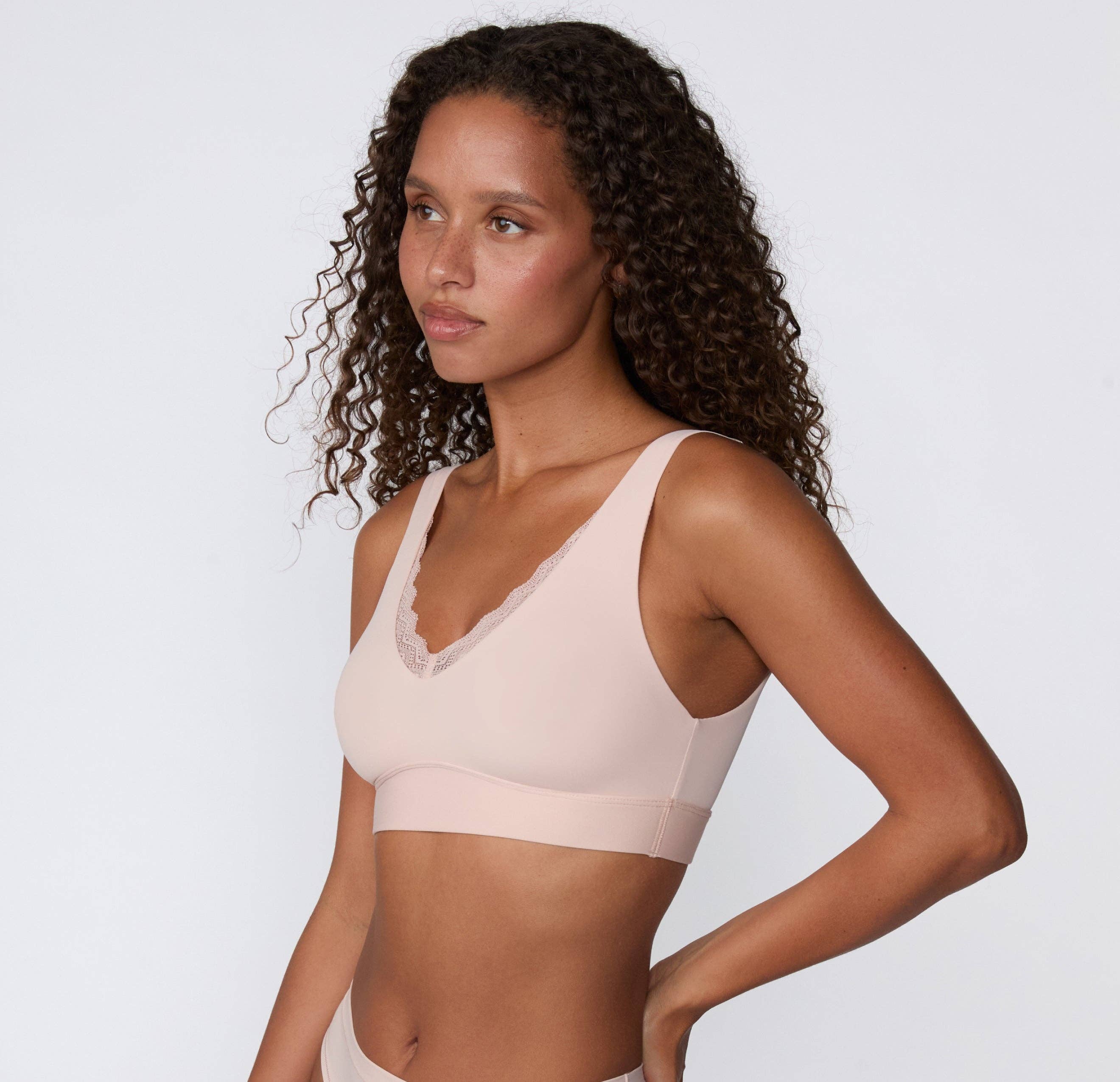 Women's blush pink pull over seamless bralette with lace side on model