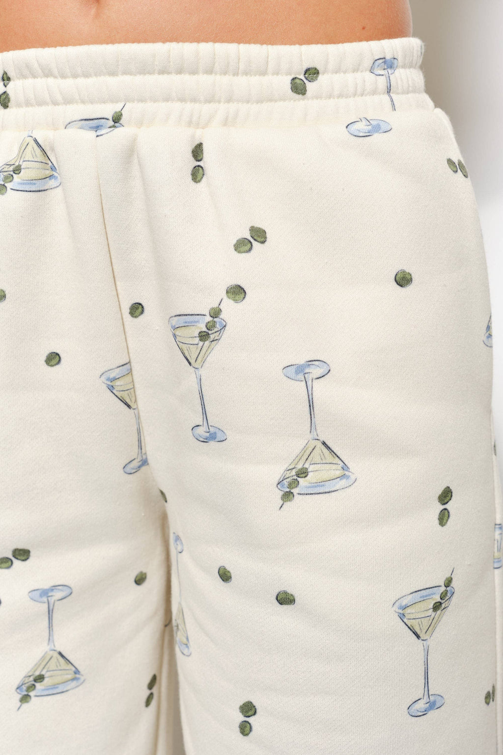Women's cream flared sweatpants with martini and olives stretchy waistband and pockets on model front detail view