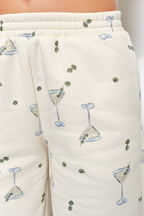 Women's cream flared sweatpants with martini and olives stretchy waistband and pockets on model front detail view