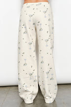 Women's cream flared sweatpants with martini and olives stretchy waistband and pockets on model back view