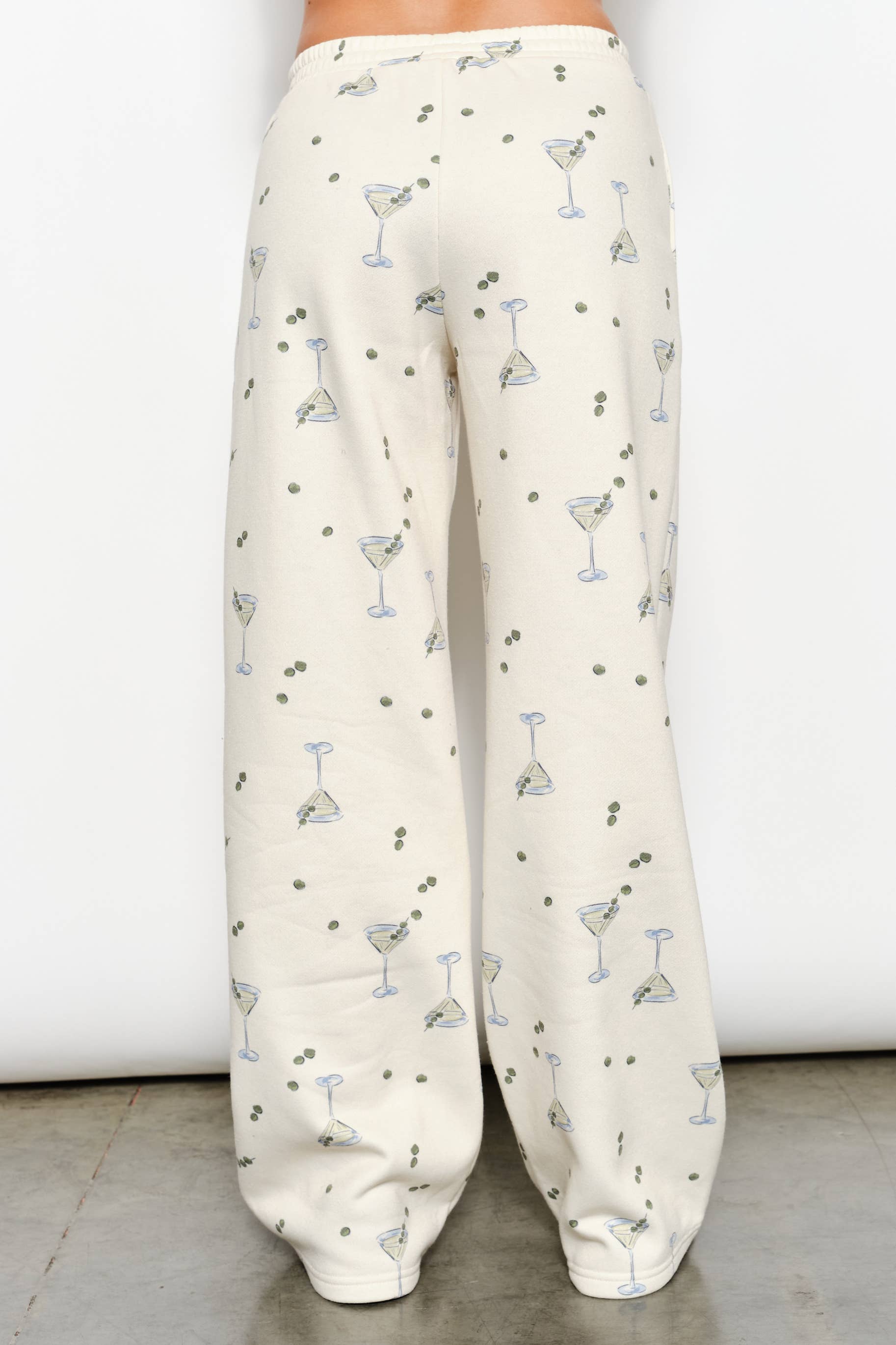 Women's cream flared sweatpants with martini and olives stretchy waistband and pockets on model back view