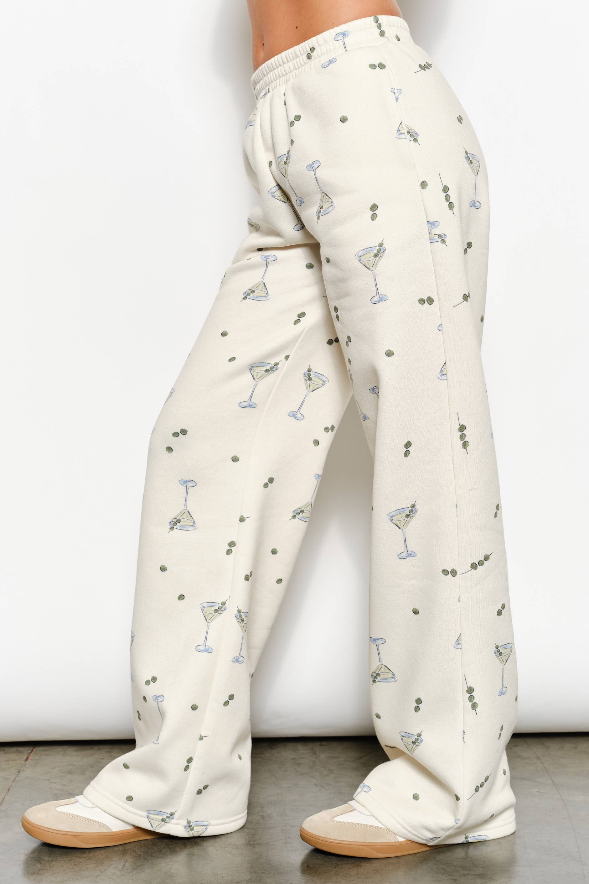 Women's cream flared sweatpants with martini and olives stretchy waistband and pockets on model side view