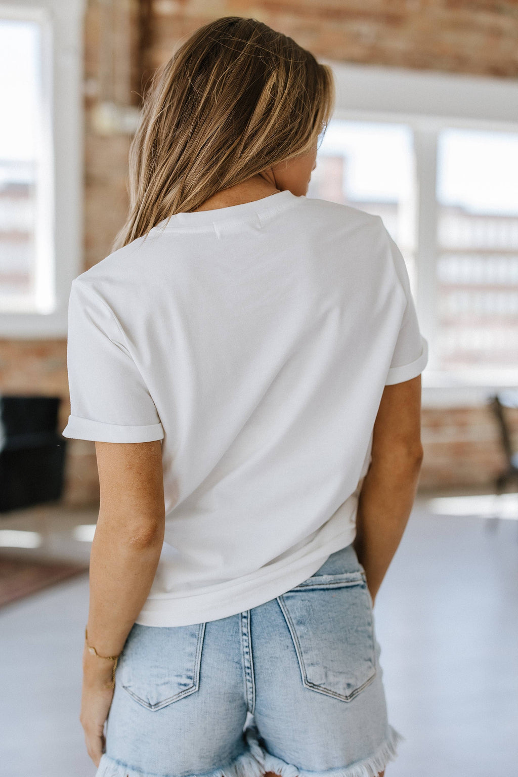 A woman wearing a white graphic tee with leopard print and the word 'mama' embroidered on the front.
