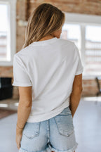 A woman wearing a white graphic tee with leopard print and the word 'mama' embroidered on the front.