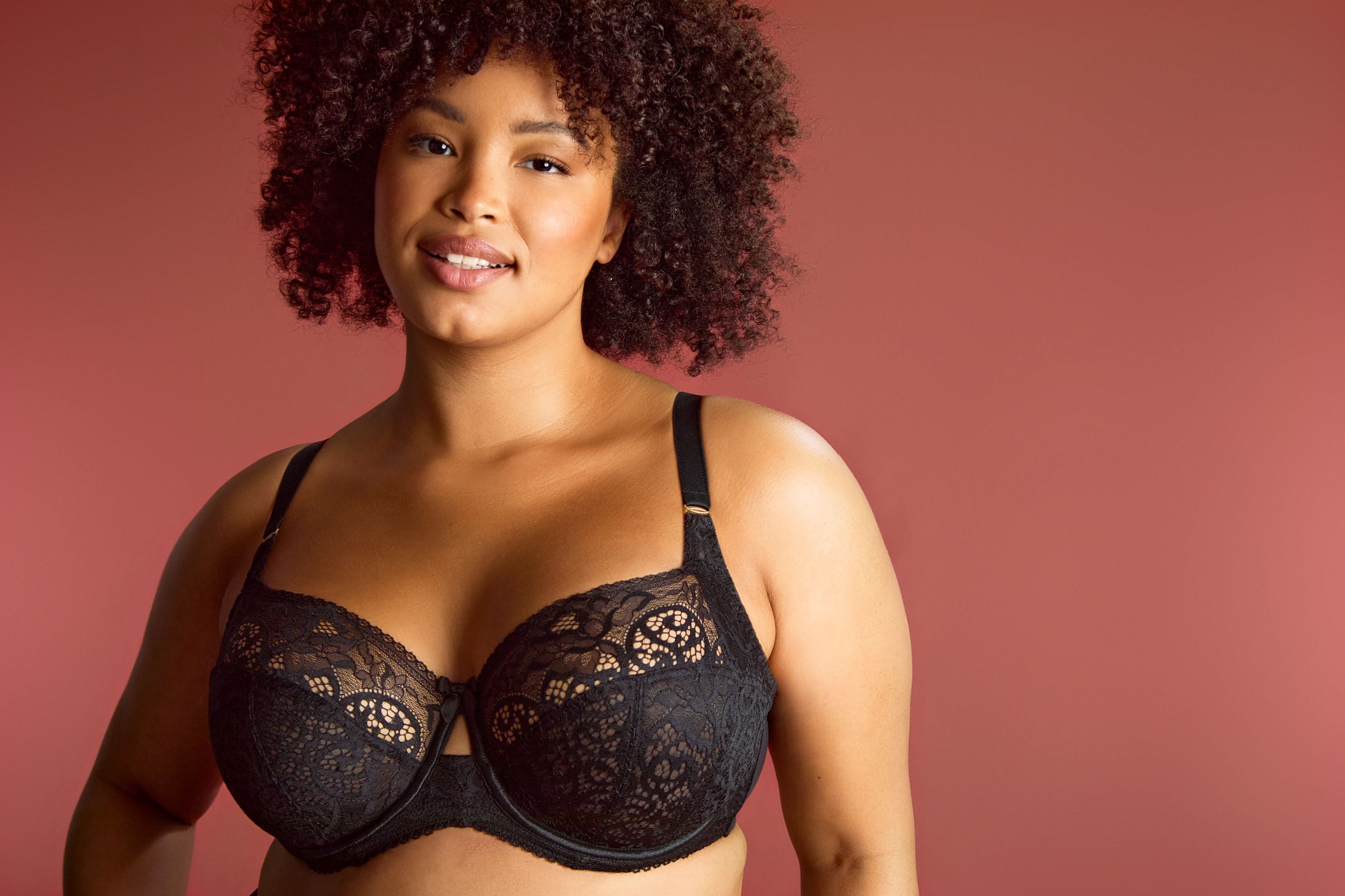 A woman wearing a black lace panache full cup bra with ornate lace detailing and a center keyhole.