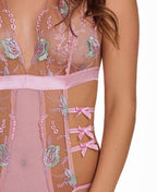 Women's pink floral embroidered lingerie bodysuit with side bows on model close detail