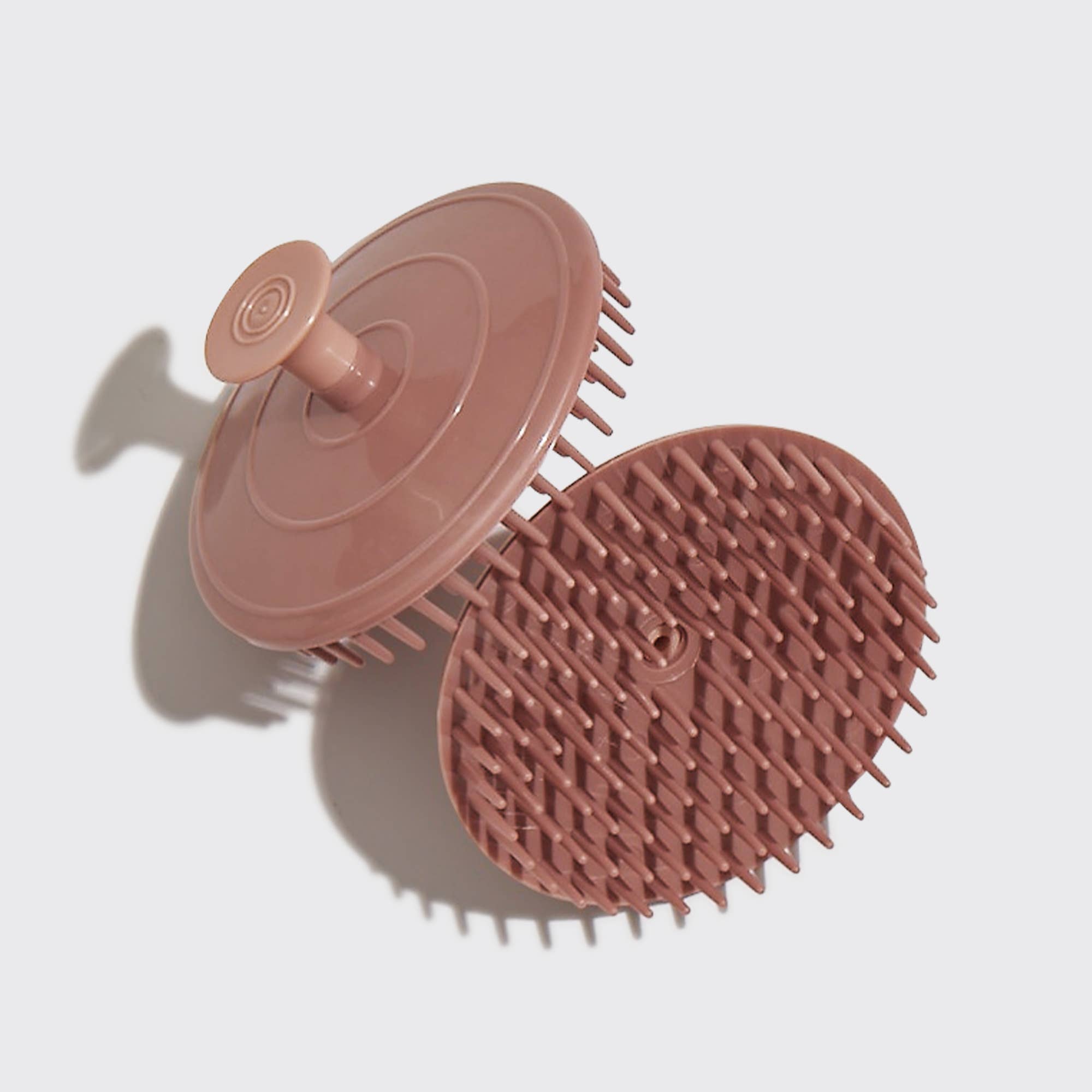 A terracotta-colored scalp exfoliator with soft, flexible bristles, designed for gentle scalp massage and hair detangling.